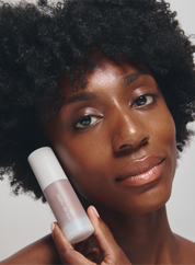 Woman holding a acne-safe product with a neutral background