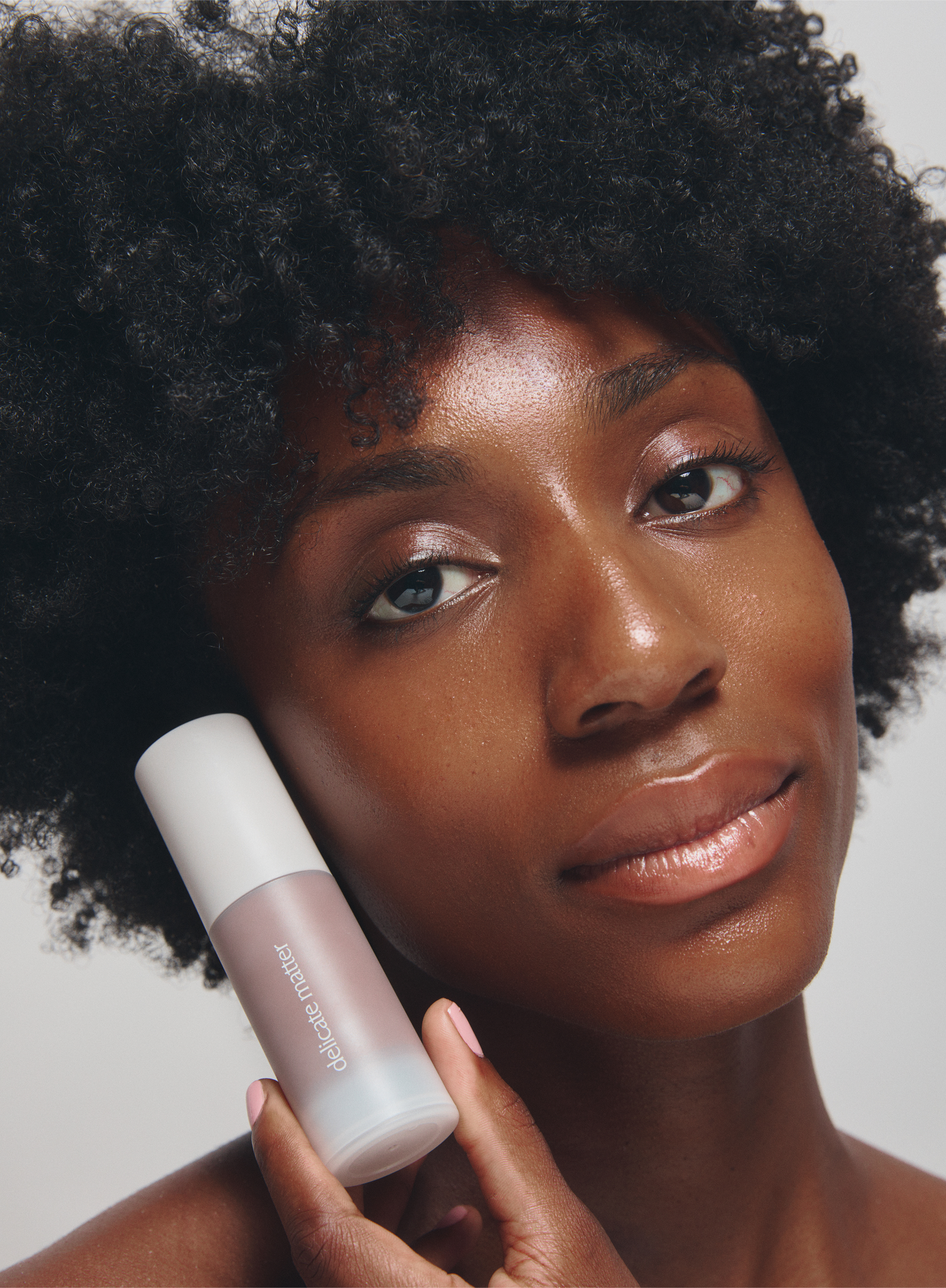 Woman holding a acne-safe product with a neutral background