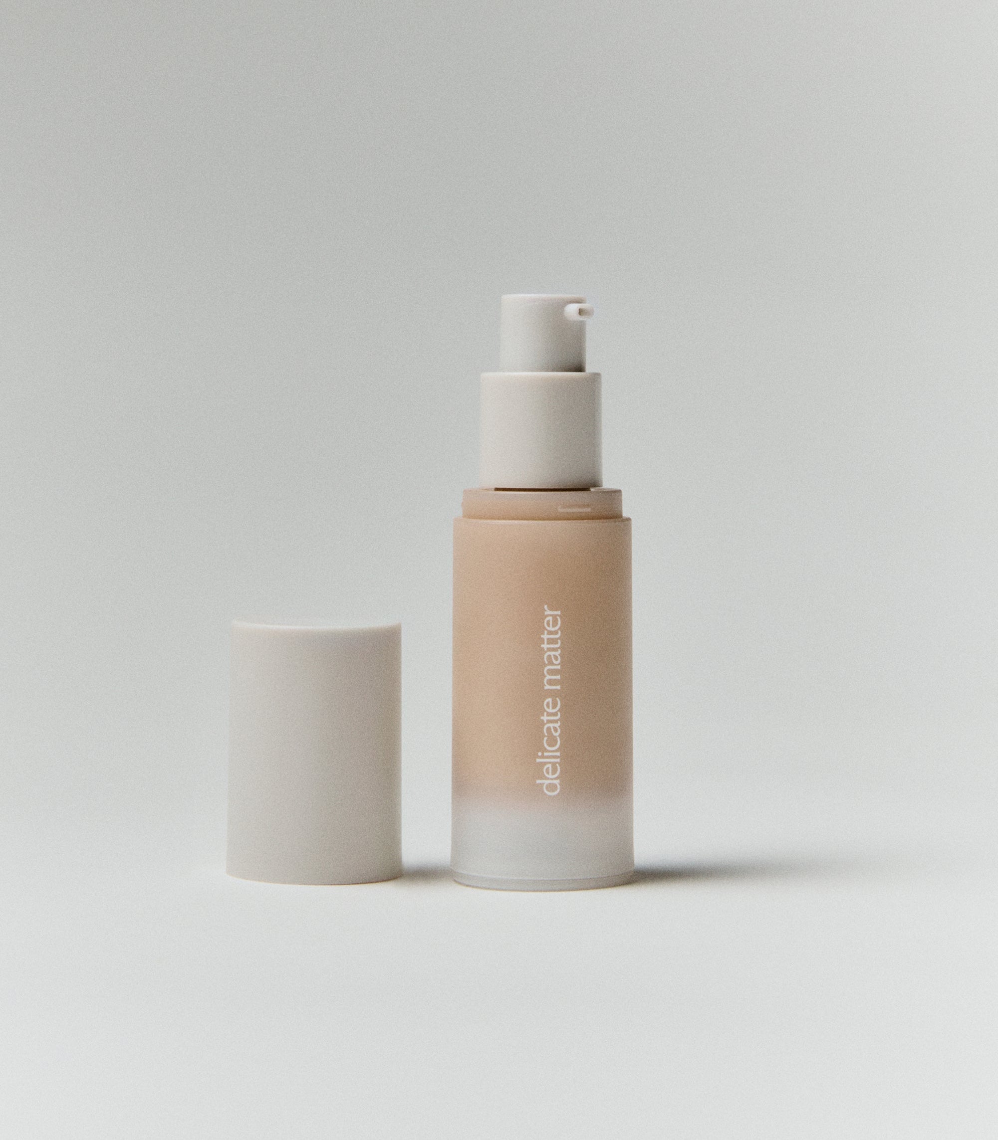 Acne-safe skin tint foundation bottle with 'delicate matter' branding on a light gray background