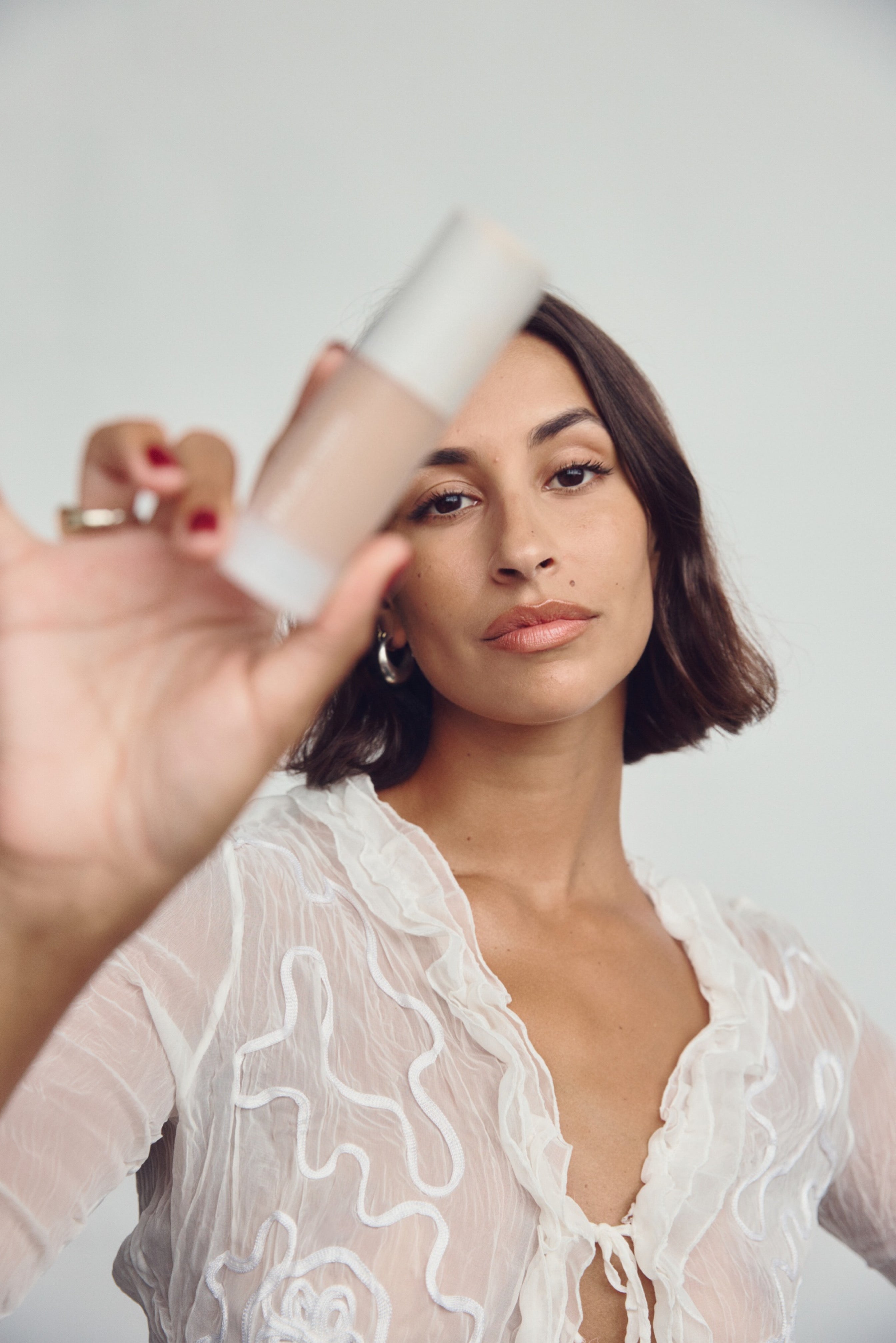 Woman with acne-safe foundation near her face with a neutral background